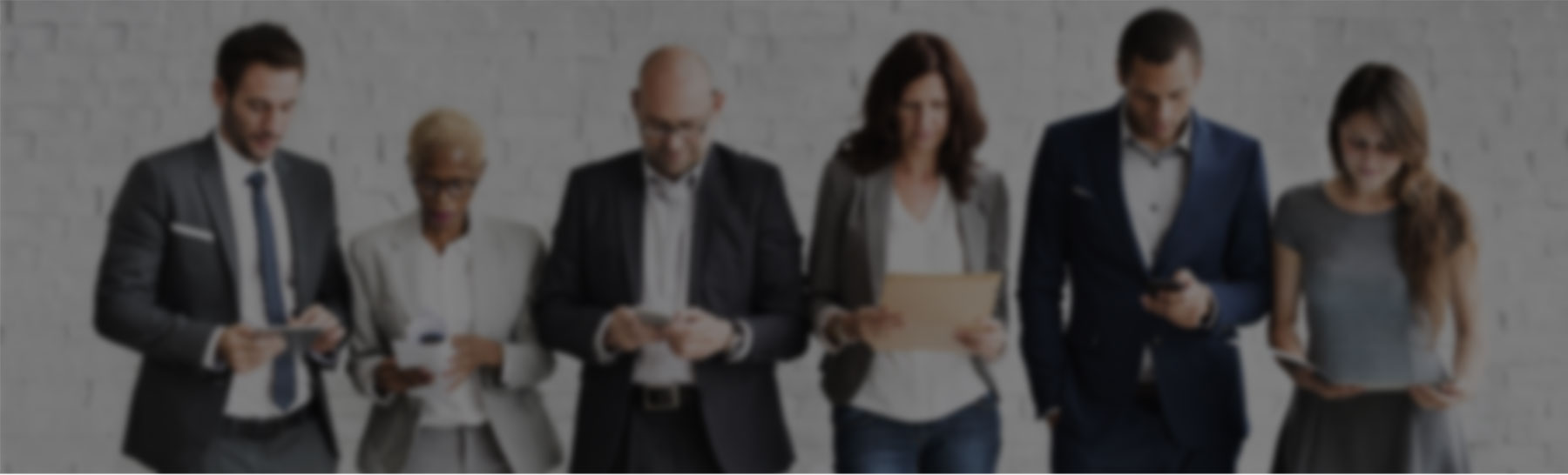 Business professionals standing in a row, engaging with documents and mobile devices.