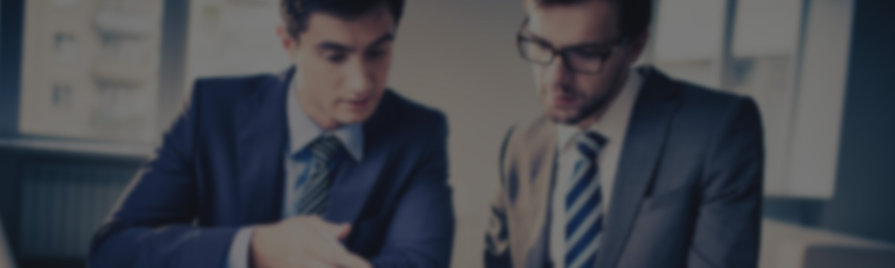 Two businessmen in suits discussing work at office.