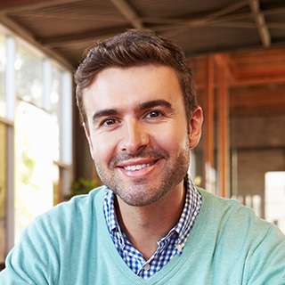 Smiling man in a casual indoor setting with natural light.