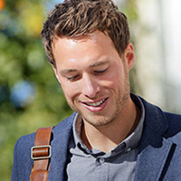 Smiling man with a backpack in outdoor setting.