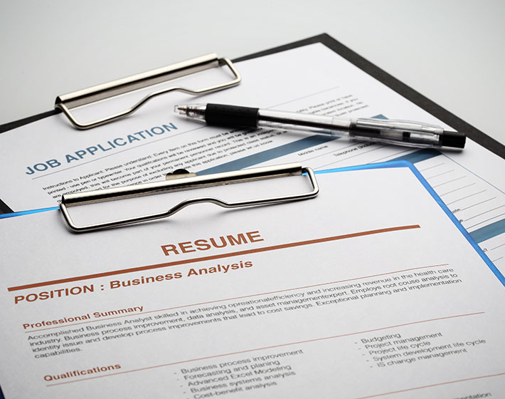 Job application and resume for a Business Analysis position with a pen on a clipboard.