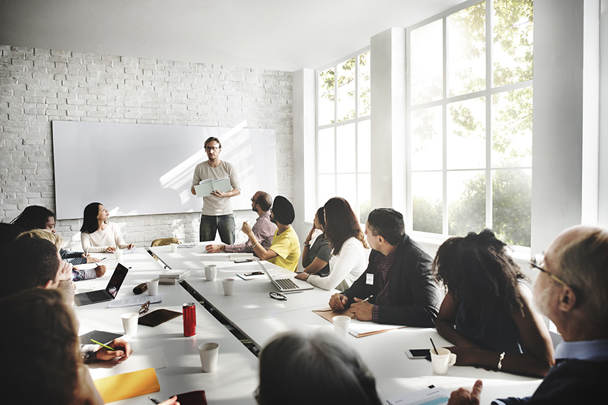 A man presenting to a diverse group in a bright conference room.