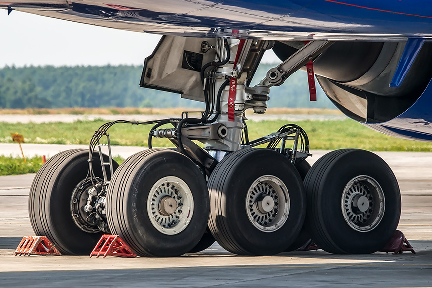 Close-up of an airplane's landing gear with multiple wheels and chocks.