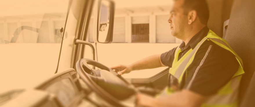 A man in a yellow safety vest driving a vehicle.