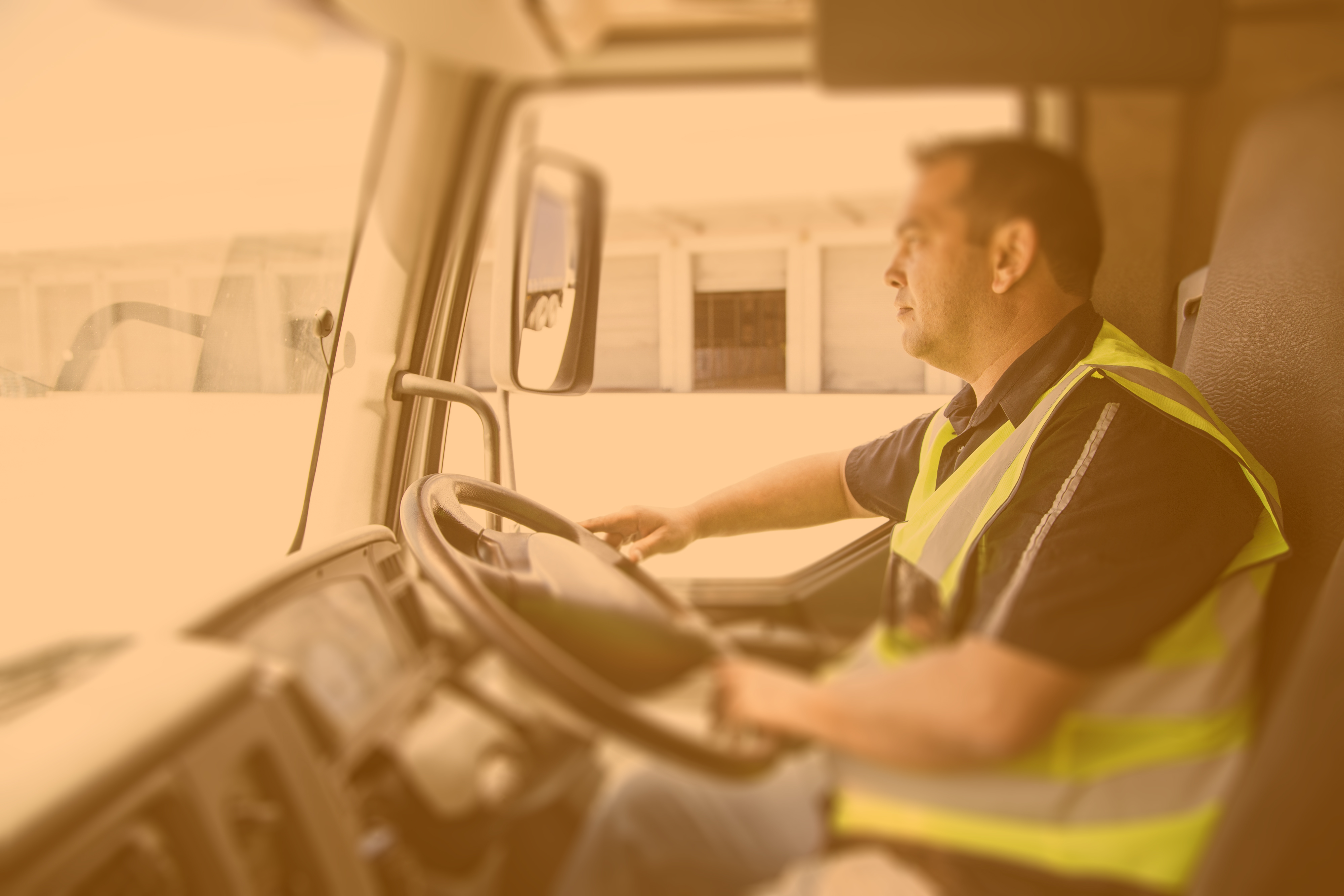 A man in a yellow safety vest driving a vehicle.