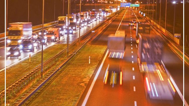 Nighttime traffic congestion on a busy highway with bright streetlights.