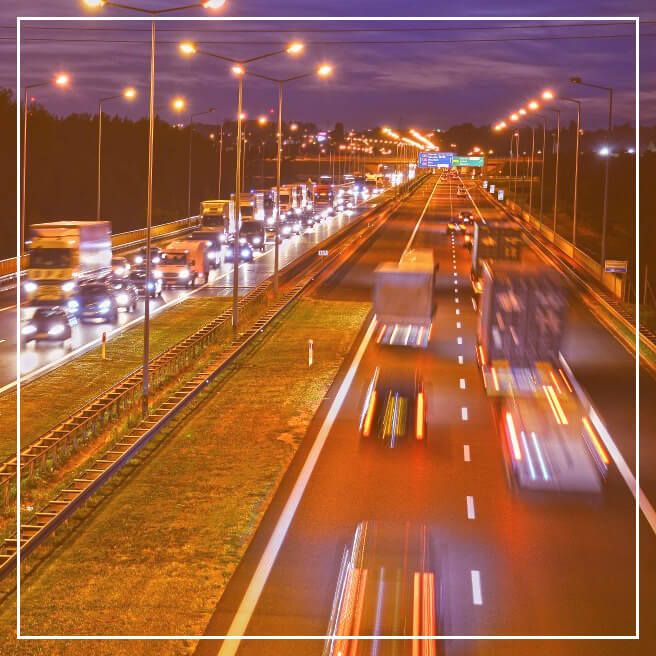 Nighttime traffic congestion on a busy highway with bright streetlights.
