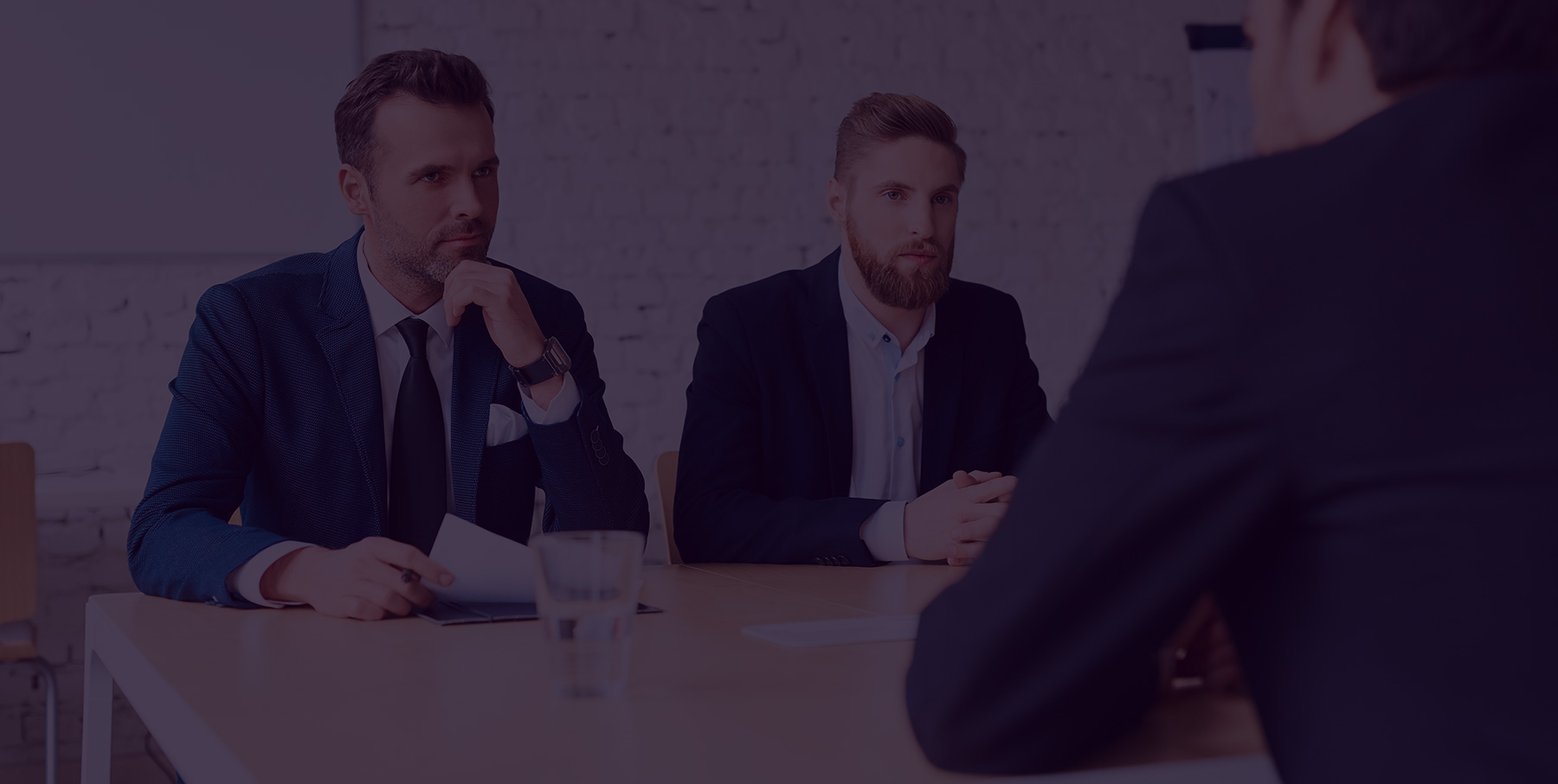 Three men in suits engaged in a serious business meeting.